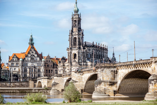 View on the riverside of Elbe river with catholic church, city gates and bridge during the sunny weather in Dresden city, Germany