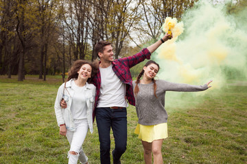 Obraz premium Youngsters walking with colored smoke in park