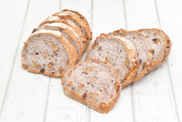 Slices of walnut bread on white wooden background
