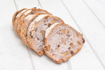 Slices of walnut bread on white wooden background
