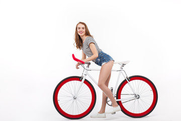Obraz na płótnie Canvas Stylish cheerful woman on bicycle in studio