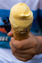 Scoop of ice in cone in the hands of a boy, close up