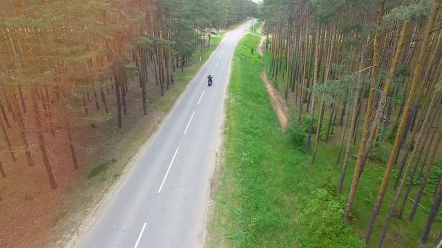 Drone video of a motorcyclist driving away.