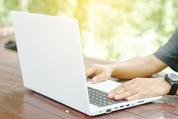 Stock photo :.Closeup image of a hands working and typing on laptop keyboard with blur nature background