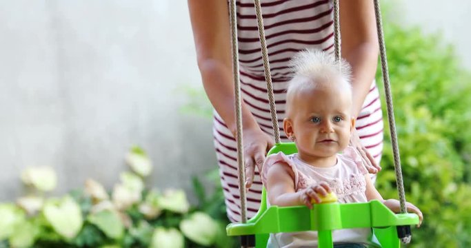 Beautiful Baby swinging outdoor with caring faimly