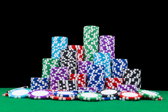 A set of poker chips stack on a green game table with a dice rolls. Black background. risk concept - playing poker in casino. Poker game theme
