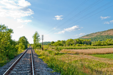 Fototapeta premium railroad track in open green field, summer time traveling