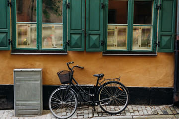 Fototapeta na wymiar the bike on the background of yellow wall with green Windows