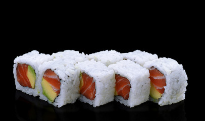 Japanese cuisine. Salmon sushi roll with avocado over black backgrond