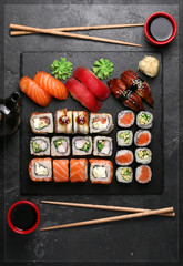 Japanese cuisine.Sushi set on a stone plate over dark concrete background.