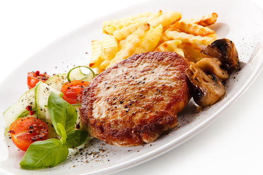 Grilled steak, French fries and vegetable salad on white background 