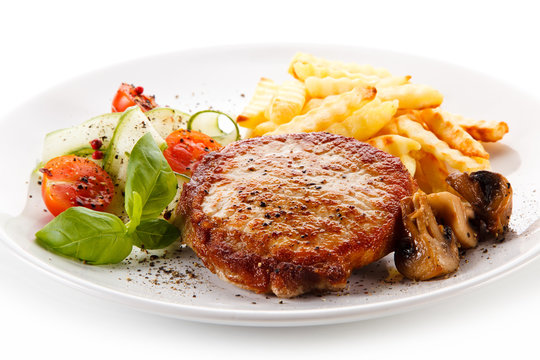 Grilled steak, French fries and vegetable salad on white background 