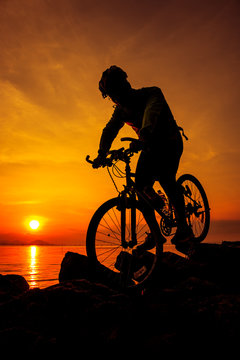 Healthy lifestyle. Silhouette of bicyclist riding the bike at seaside. Outdoors.