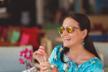 Elegant woman with sunglasses enjoying iced coffee  at a cafe, selective focus