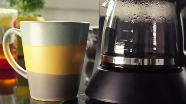 Hot Steam Black Coffee In Morning Breakfast. Hot coffee served in a mug next to coffee maker in a breakfast table