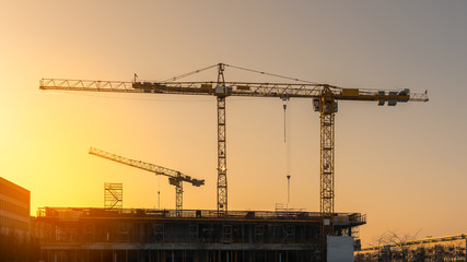 Industrial construction cranes and building silhouettes