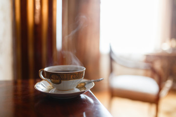 The smell of coffee in vintage mugs, couple in an expensive interior on the background of the window. Mug with pattern on saucer and spoon