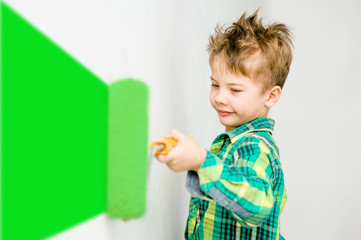 Happy young boy painting the wall with paint roller