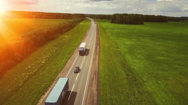 Beautiful landscape with a ride on the highway the trucks and a few cars at sunset. aerial view