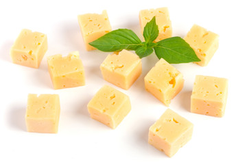 cheese cut into cubes with basil leaves isolated on white background