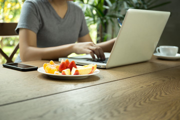 Select focus young asian woman working on laptop with fresh fruit