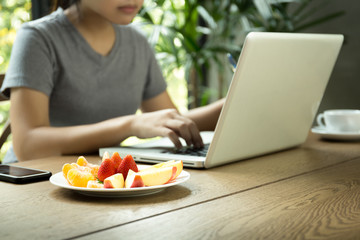 Young asian woman study working on laptop with fresh fruit