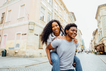 Smiling afro american couple of lovers having fun in city street in summer time -tourism, travel,...