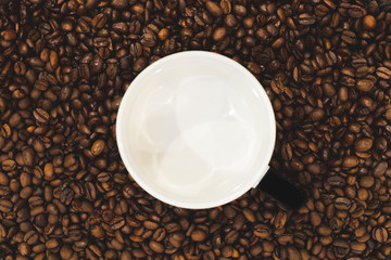 coffee beans around empty cup