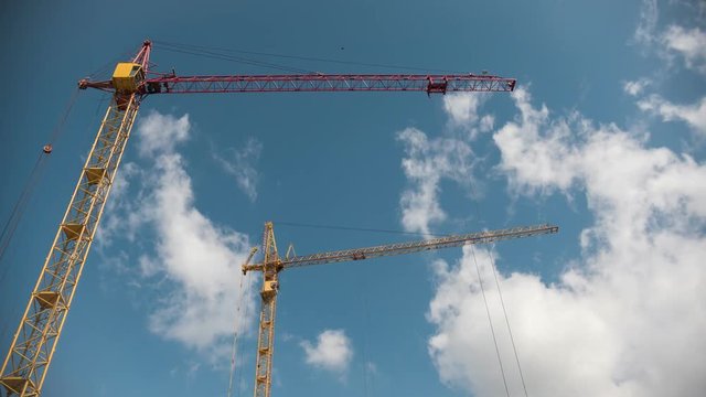 Working crane in construction site in fronr of blue sky, time-lapse
