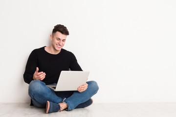 Smiling young man freelancer in casual with laptop