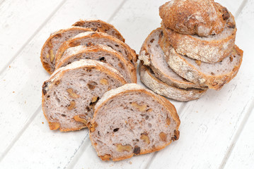 Slices of walnut bread on white wooden background