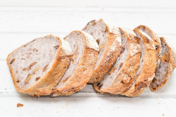 Slices of walnut bread on white wooden background