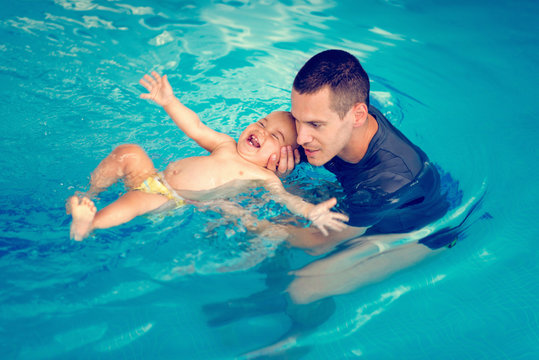 Swimming instructor with cheerful baby boy on swimming class