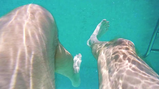 Man swimming in the pool - closeup of legs under water - slowmotion