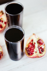 Pomegranate juice in glass surrounded by pomegranate halves.