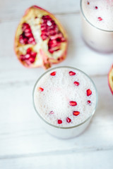 Traditional indian lassi - cold yougurt drink on white table with pomegranate seeds