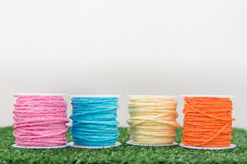 Four of colorful thread on grass with white background