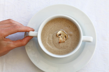 Woman hand holding tureen of champignon cream soup