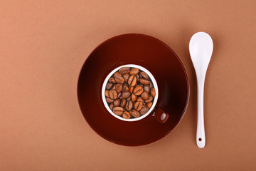 Brown cup of roasted coffee beans on parchment
