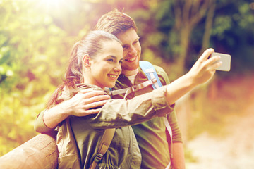 couple with backpacks taking selfie by smartphone