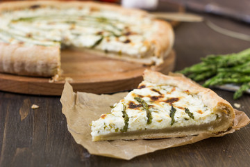 Fototapeta na wymiar Piece of delicious asparagus pie on list of parchment.