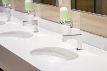 Water tap with soap press inside clean public restroom