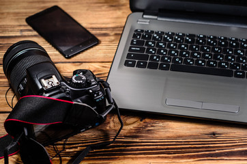Modern DSLR camera and laptop on wooden table