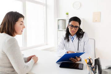 Obraz premium doctor with clipboard and woman patient at clinic