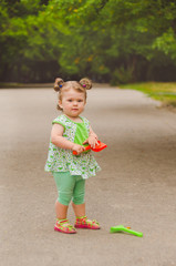 Portrait of a little girl in the alley with a toy