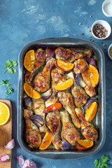 Pieces of chicken baked with oranges and red onions. Top view, vertical photo
