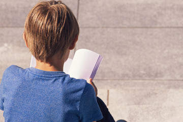 Young boy reading book outdoors
