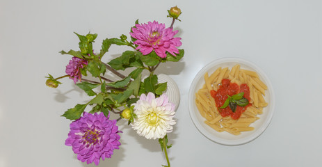 Schön angerichtetes Essen mit Blumen auf dem Tisch - Pasta mit Tomaten Sauce