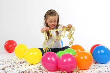 Fototapeta na wymiar Blondes Mädchen sitzt zwischen Ballons und Konfetti