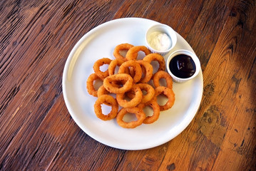 Fried Onion Rings and sauces on wooden table